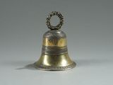 brass bell with a ring on top of it on a white surface
