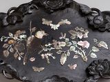 a black plate with a bird and flowers on it
