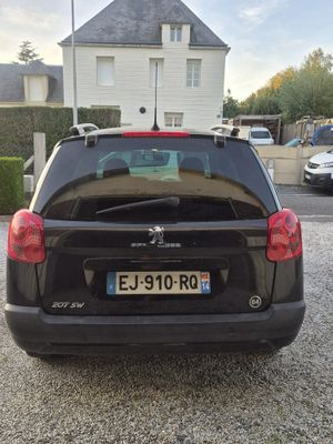 une petite voiture noire garée devant une maison blanche