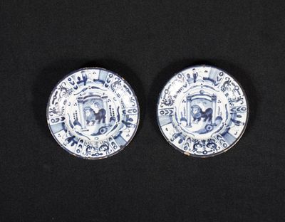 deux assiettes bleues et blanches posées sur une surface noire, sur fond noir