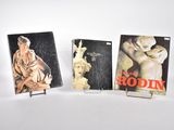 trois livres sur un fond blanc, avec une statue de femme et une statue d'homme