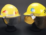 two yellow hard hats with face shields on top of each other