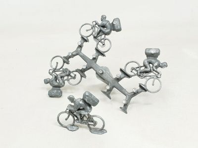 three miniature figurines of people riding bicycles