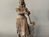 an old statue of a woman holding a pot and a shovel