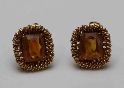 une photo d'une paire de boucles d'oreilles ornées d'une pierre de couleur dorée
