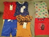 several children ' s clothing are laid out on a couch