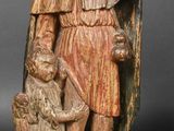 an old wooden statue of a man holding a child and a dog