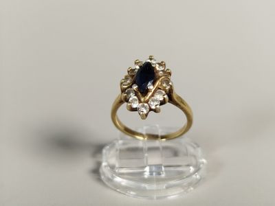 gros plan d'une bague en or avec un saphir et des diamants