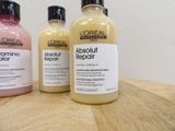 three bottles of hair products sitting on a wooden table