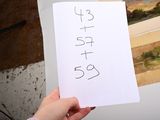a person holding up a piece of paper with numbers on it