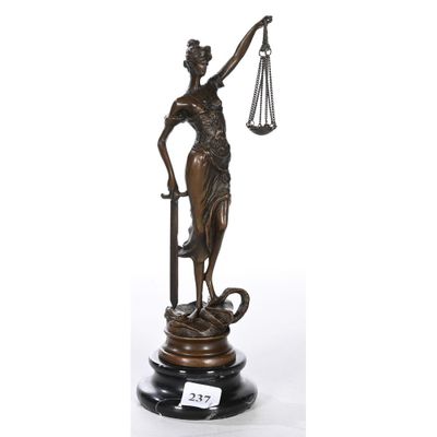 une statue en bronze représentant une femme tenant une balance et une épée