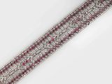 a close up of a diamond and ruby bracelet on a white surface