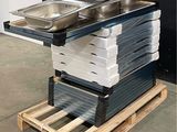 Plusieurs plateaux de nourriture sont empilés sur une palette devant un mur noir
