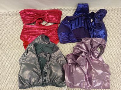 quatre vêtements brillants de couleurs différentes posés sur un lit