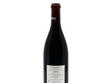 the bottle of red wine is sitting on a white surface