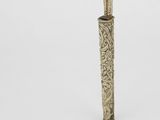 un stylo argenté et vert et un couteau posés sur une surface blanche