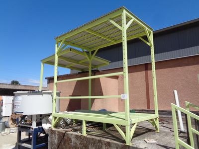 a green metal structure sitting on the side of a building