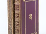 un vieux livre posé sur une table blanche, à côté d'un livre violet