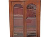 a wooden cabinet with two glass doors and a rug on the floor