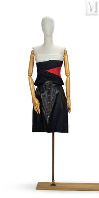 mannequin féminin vêtu d'une robe noire et rouge, posé sur un socle en bois