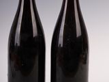 two bottles of wine sitting next to each other on a white surface