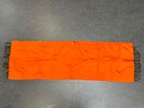 an orange table runner with fringes on top of a gray floor