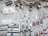 a lot of silverware on a table with a bowl and spoons
