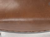 a close up of a brown leather chair on a white surface