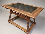 une vieille table en bois avec un plateau en verre et des pieds en bois