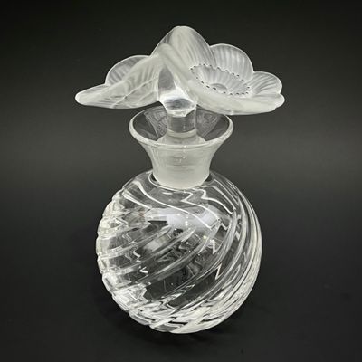 un vase en verre contenant une fleur, posé sur une surface noire