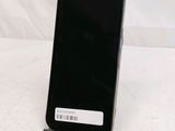 a black cell phone sitting on a stand on a white surface