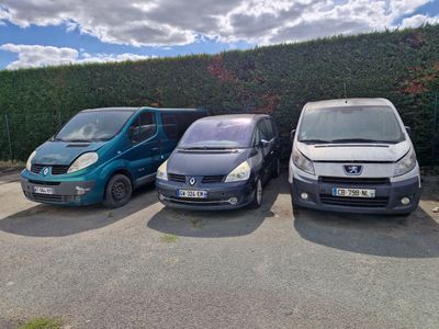 Trois petites voitures sont garées sur un parking à côté d'une haie.