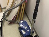 un aspirateur posé sur un bureau, à côté d'une pile de papiers