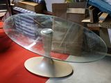 a glass table with a metal base on a red carpet