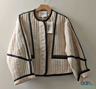 beige and black jacket hanging on a hanger on a wall