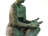 statue d'une femme assise sur un rocher, en train de lire un livre