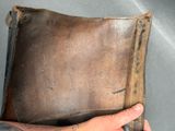 a person holding a brown leather case with a tattoo on it