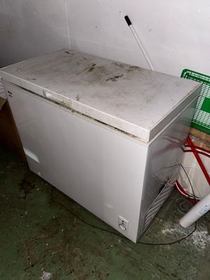 un congélateur coffre blanc posé dans une pièce sale
