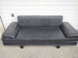 a black leather couch sitting in front of a garage door