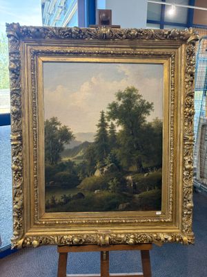 une peinture à l'huile représentant un paysage, posée sur un chevalet dans une pièce