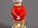 a small figurine of a teddy bear wearing a red coat