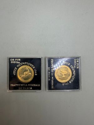Deux pièces d'or et d'argent sont exposées dans une vitrine.