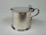 a silver cup with a handle on a white table
