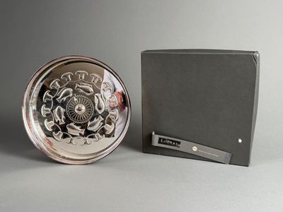 une horloge en argent posée à côté d'une boîte sur une table