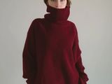 the woman is wearing a red sweater and black pants