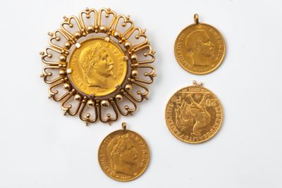 un gros plan sur trois pièces d'or et un pendentif posés sur une surface blanche