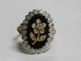 une image représentant une bague noire et dorée ornée d'une fleur