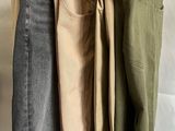 three pairs of jeans hanging on a rack in a room