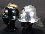 pair of firemen ' s helmets on display against a black background