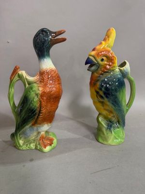 two ceramic birds that are sitting on a pitcher